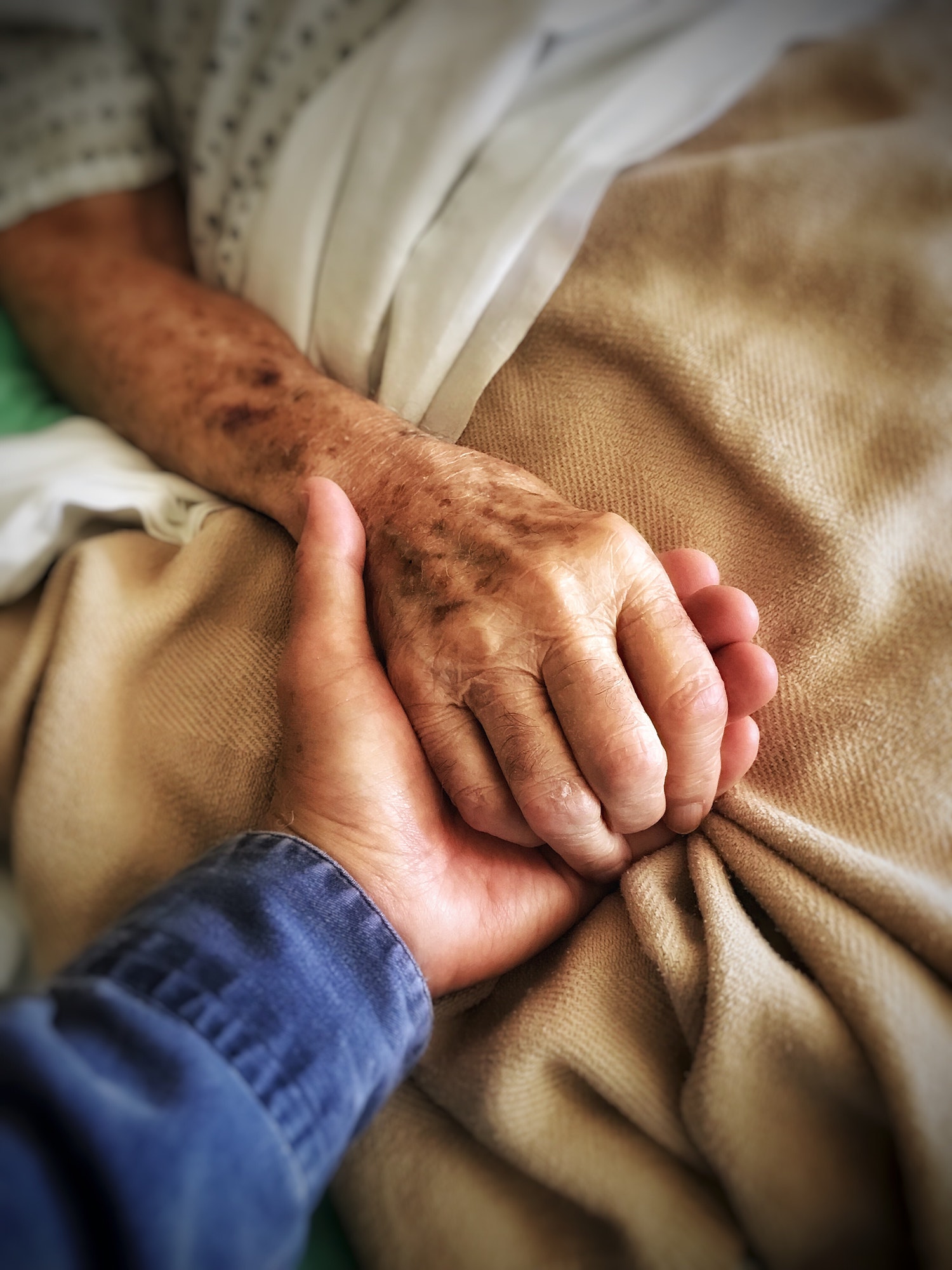 Son holds his dying father’s hand at hospital bedside