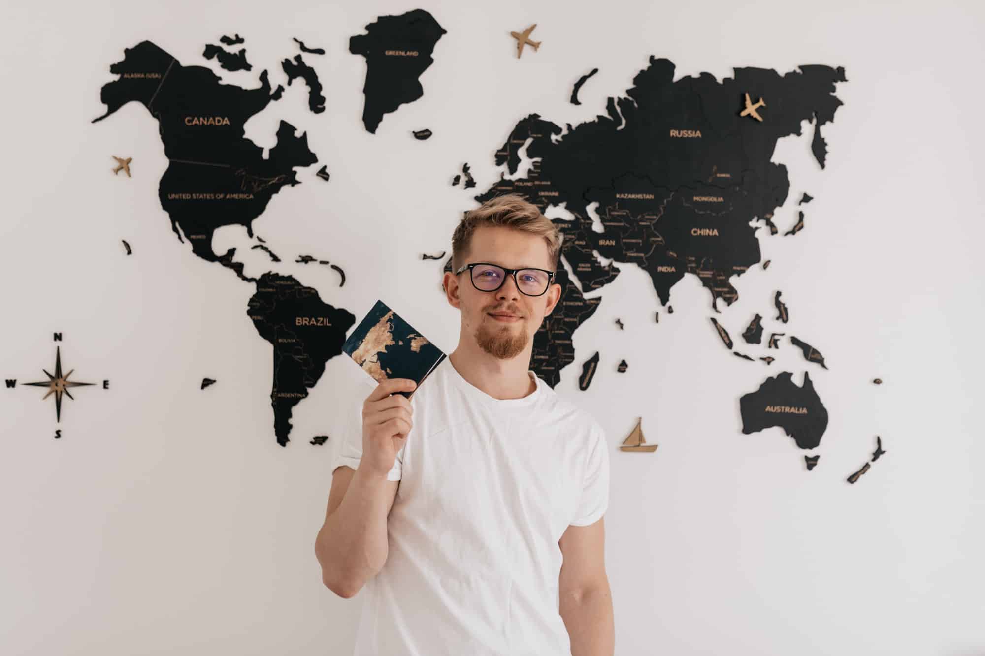 Stylish european man with passport posing at camera over world map.