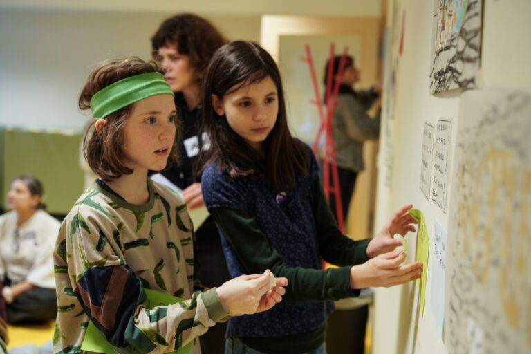 Kinder kleben Zettel an eine Wand bei der Kinderuni